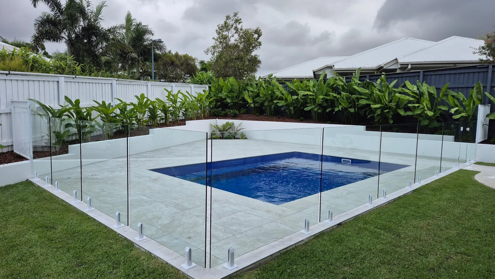 Frameless glass pool fence installed around a backyard pool on the Sunshine Coast