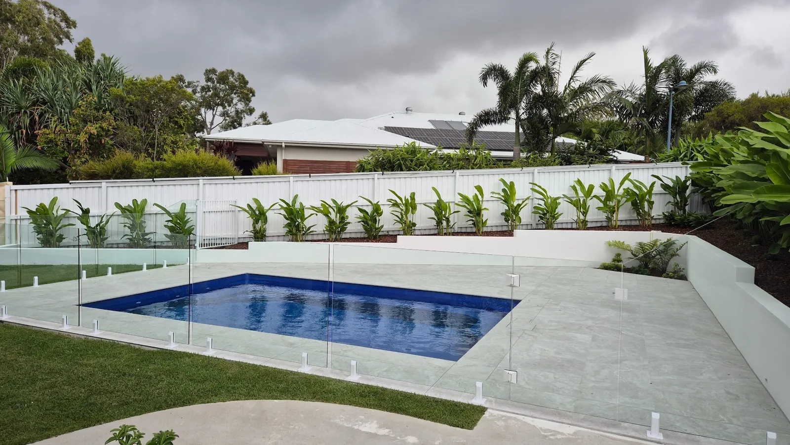 Wide view of the completed glass pool fence with landscaped surrounds