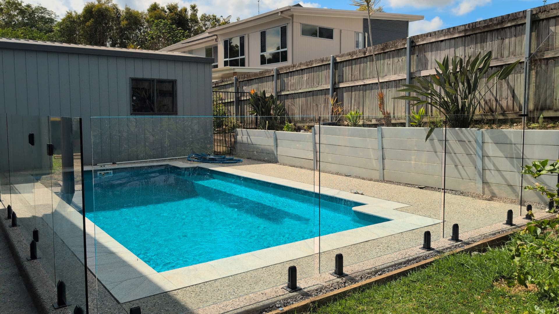 Frameless glass pool fence around backyard pool