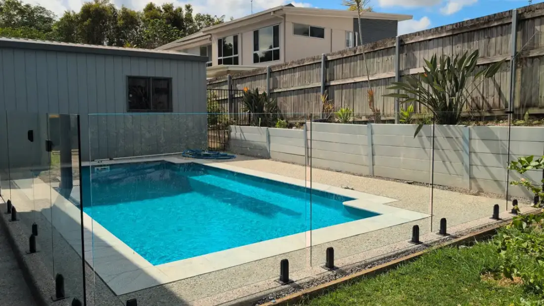 Frameless glass pool fence around backyard pool