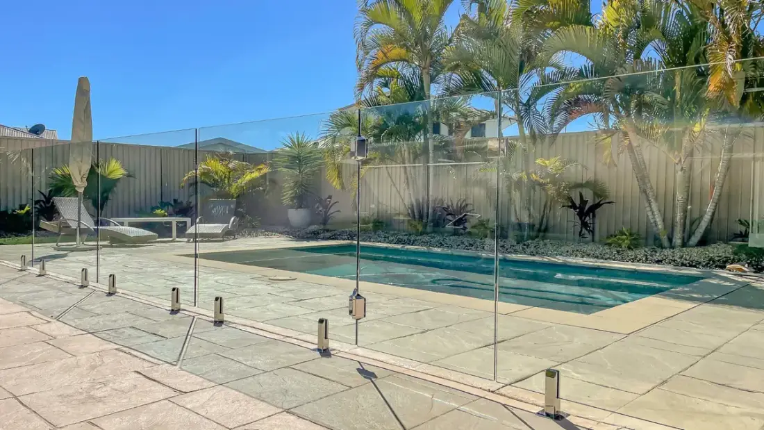 Frameless glass pool fence with tropical palm surrounds